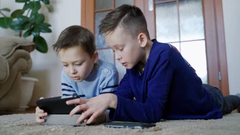 two cute boys playing video game with smartphone indoors, close-up