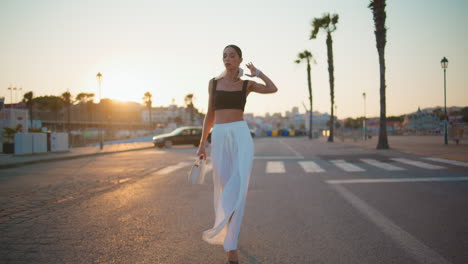 stylish woman walking on a city street at sunset