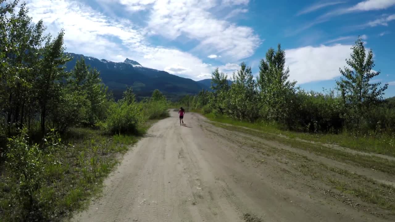 Rear view of fit woman jogging through road 4k
