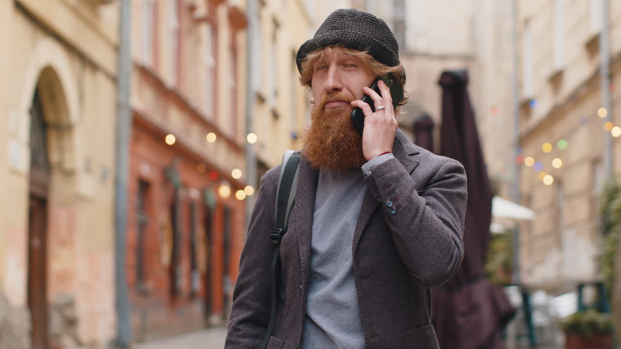 Happy young man having remote conversation talking on smartphone good news gossip in city street