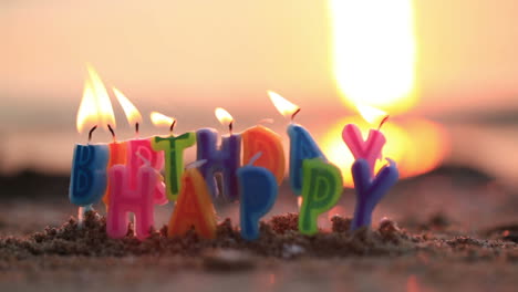 velas de cumpleaños ardiendo en una orilla del mar