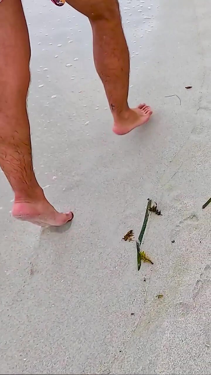 Una persona corre a piedi nudi sulla sabbia bagnata, lasciando impronte vicino alla dolce marea dell'oceano