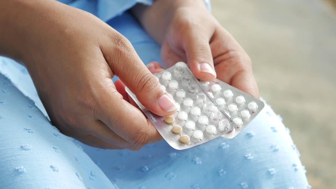 Mano de mujer sosteniendo píldoras anticonceptivas cerrar