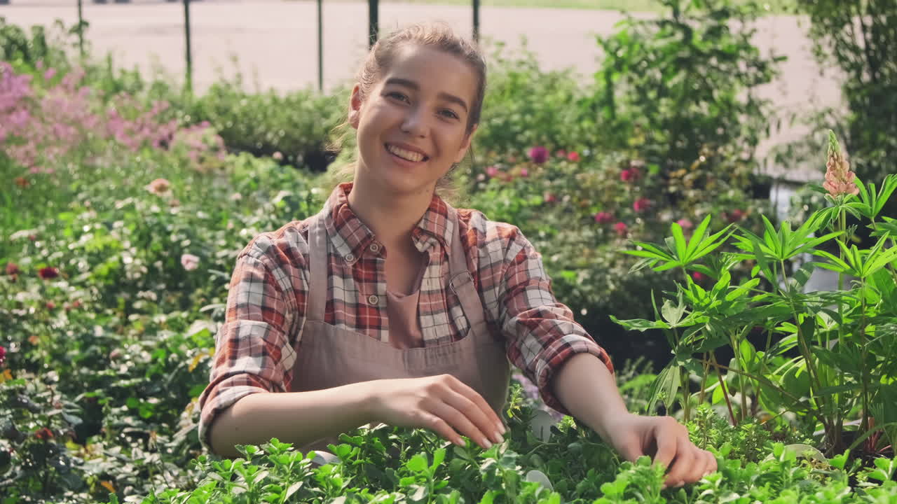 Woman working in a garden center surrounded by plants and flowers