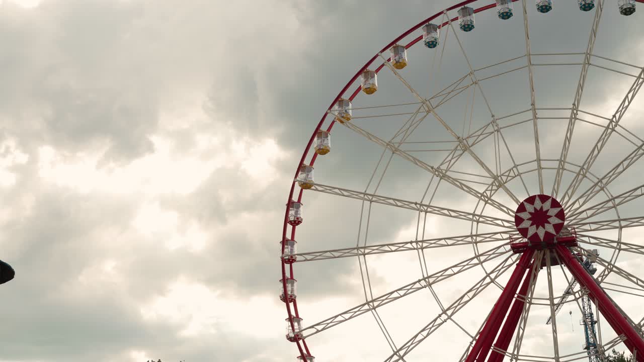 la gran rueda de ferris en el parque de atracciones gira contra el cielo nublado