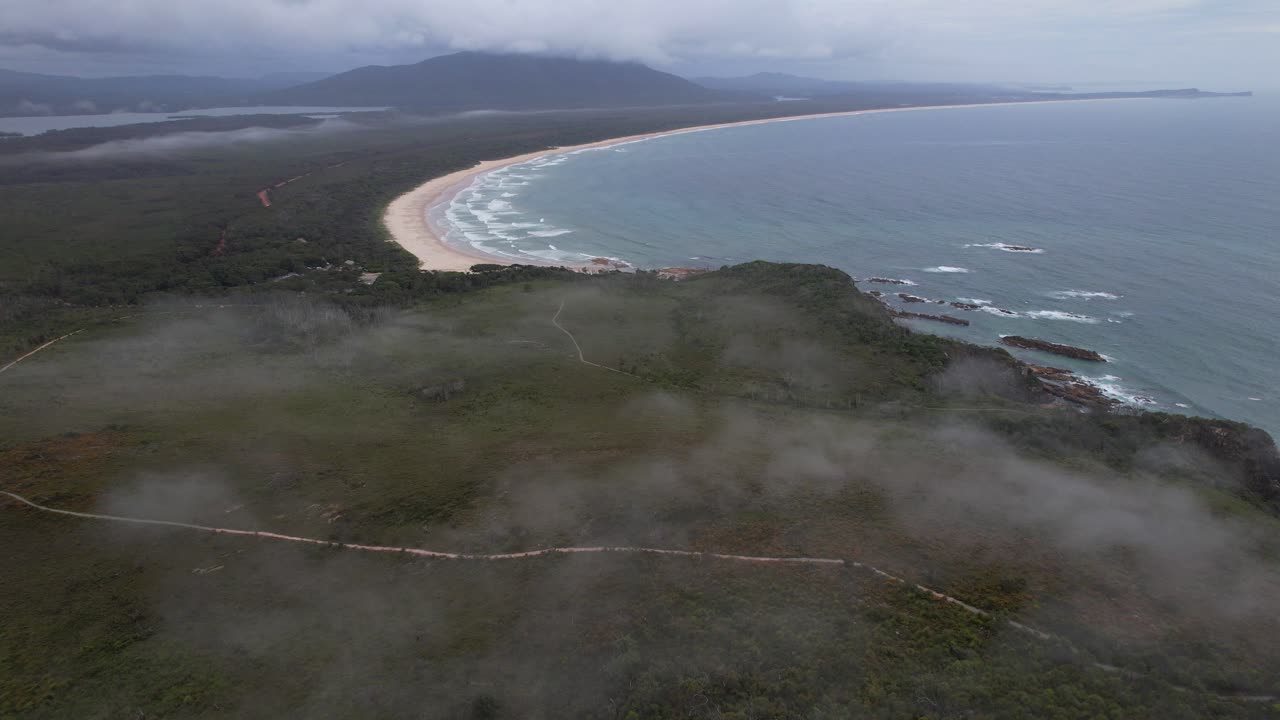 Fog Clouds Over Forested Headland Of Diamond Head Beach On Crowdy Bay, NSW, Australia. aerial shot