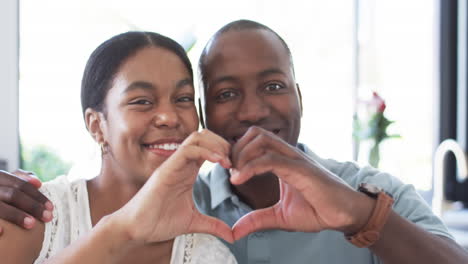 a diverse couple forms a heart shape with their hands