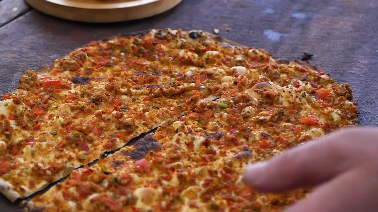 Taglio di Lahmacun appena sfornato su un tavolo di legno rustico