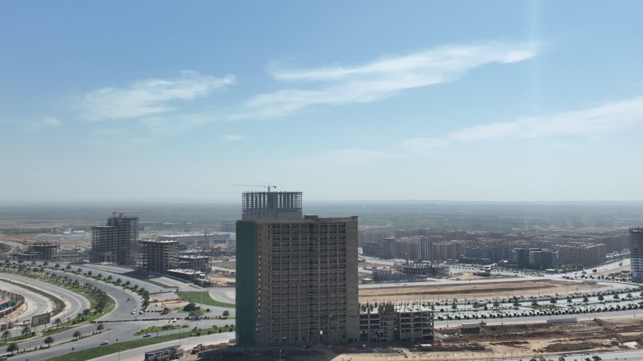 un avión no tripulado se mueve hacia adelante en una toma de un edificio de varios pisos en construcción cerca de la rotonda de sindh square en la ciudad de bahria, karachi, pakistán en un día soleado