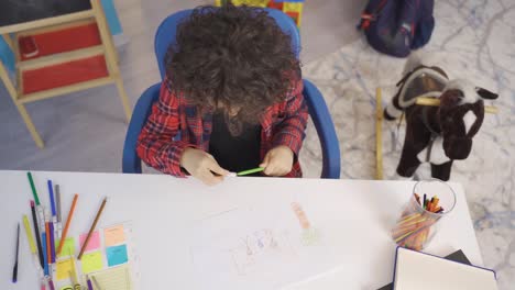 Little-boy-draws-a-picture-on-paper-with-colored-pencils.