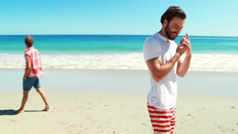 men walking on beach while talking on mobile phone