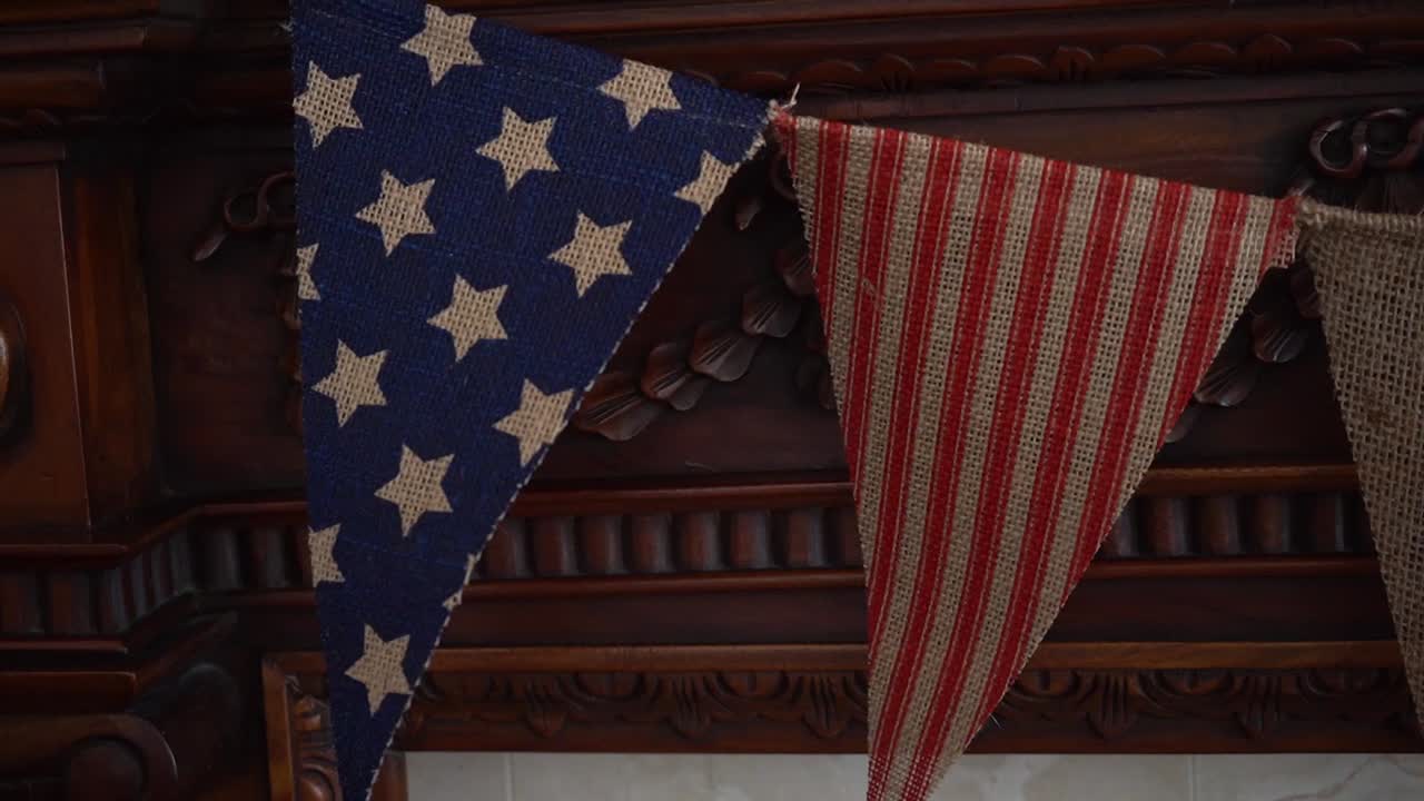 Close up of American stars and stripes flags hanging on a wooden fireplace mantle