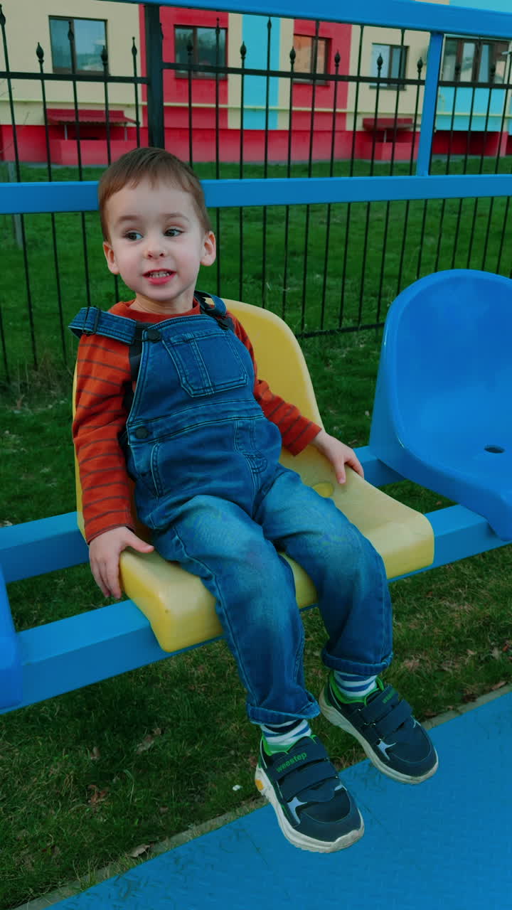 Park outdoor kid having fun. Young baby boy sitting on the bench. Vertical video.