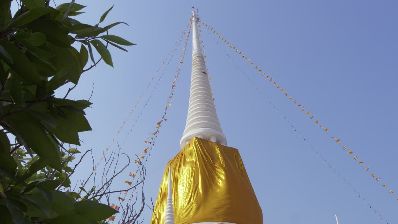 Assisti alla vivace cerimonia intorno a una splendida stupa dorata in Thailandia sotto il cielo azzurro e limpido.