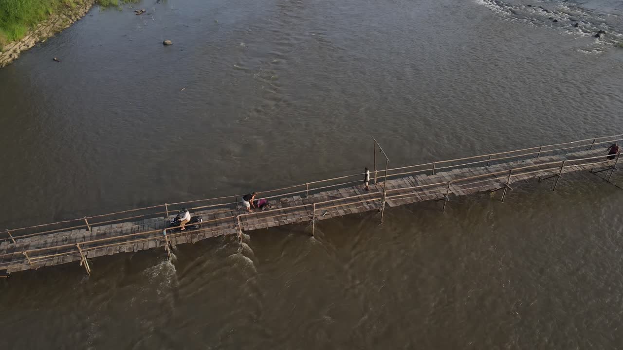 Aerial footage shows a wooden bridge spanning the Progo River, passable by motorbikes. As a link between the villages of Bantul and Kulonprogo.