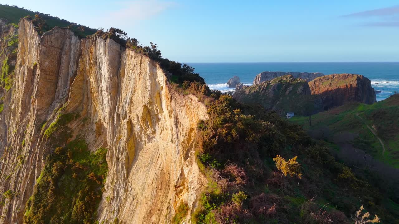 Aerial view of steep cliffs dropping into ocean with waves below