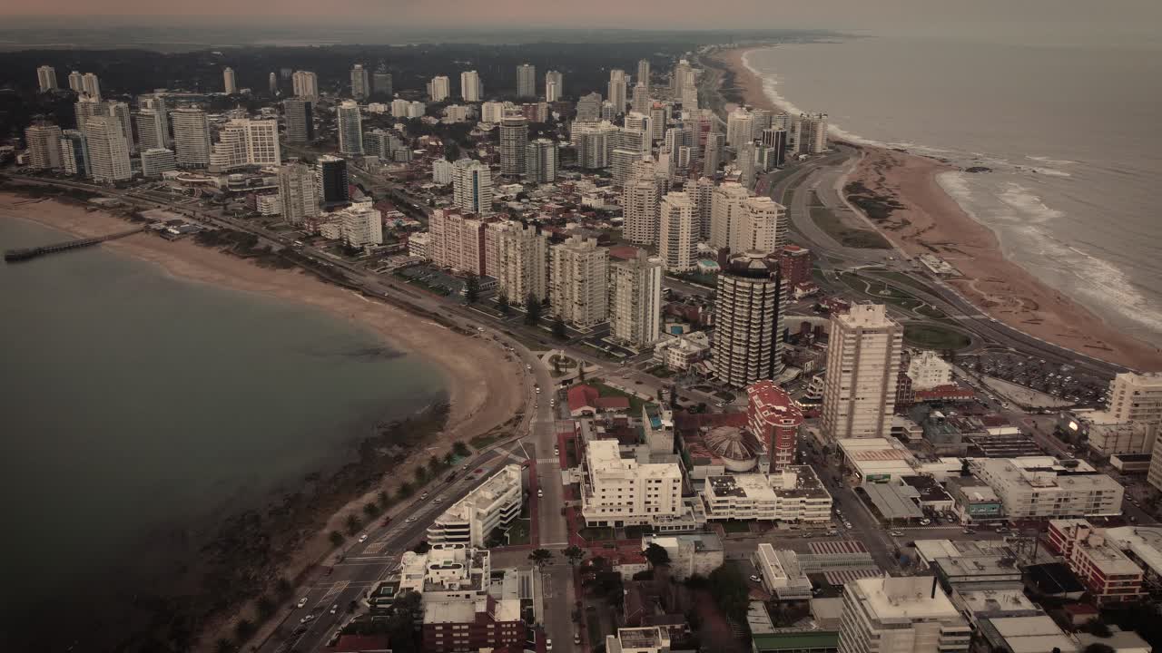 toma aérea cinematográfica de la ciudad de punta del este con playa de arena y edificios rascacielos en la isla durante el día místico - uruguay, sudamérica