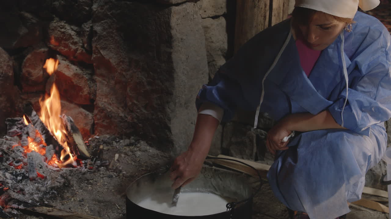 mujer artesana durante el proceso de elaboración del queso en la cocina tradicional con hogar