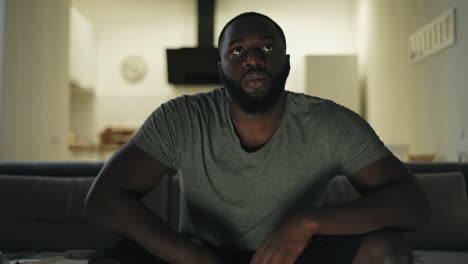 concentrated man watching football game on tv. angry guy going out in darkness