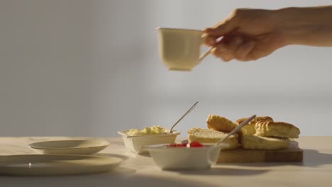 studio shot of person with traditional british afternoon tea with scones cream and jam