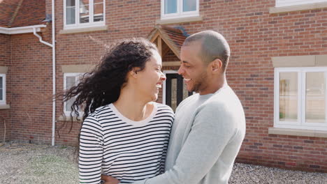 loving couple standing outside new home on moving day