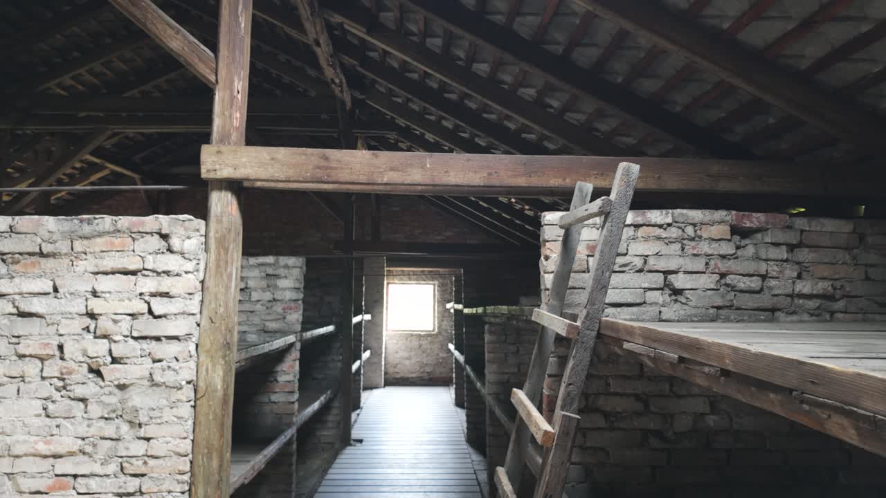Wooden bunks and ladder in dim barracks at Auschwitz-Birkenau, Poland