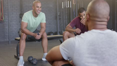 happy diverse group sitting and talking after training in fitness class at gym, in slow motion