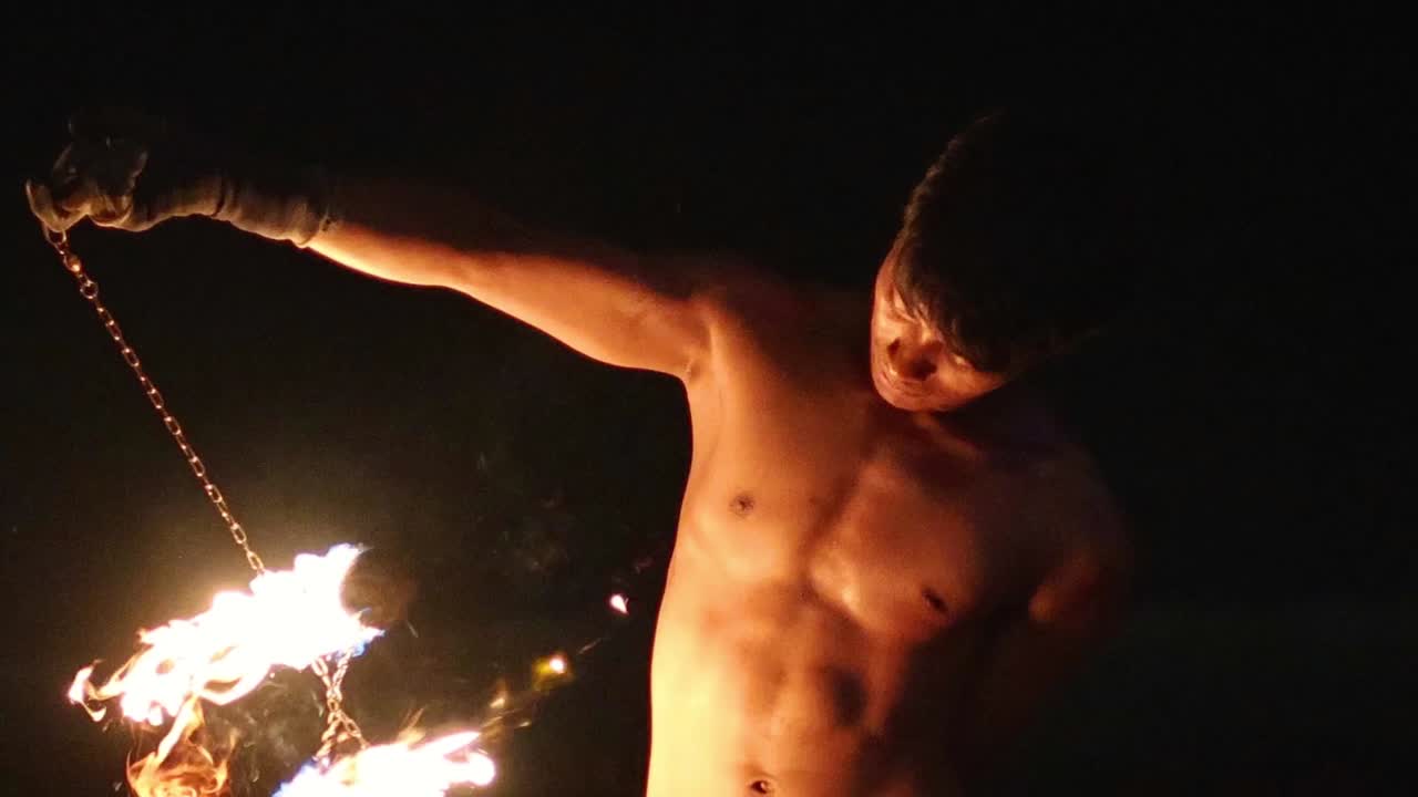 Two performers skillfully spin fire chains in a captivating nighttime display of coordination and artistry.