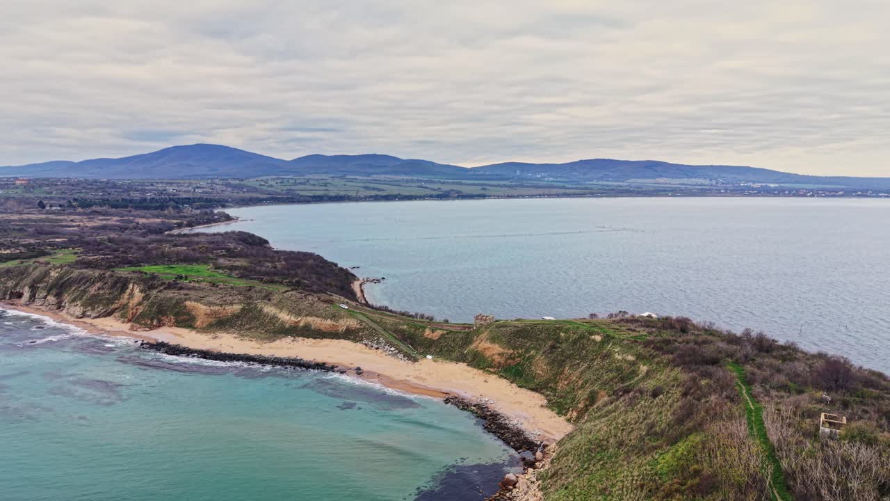 Scenic aerial view of coastal landscape with rolling hills and calm waters