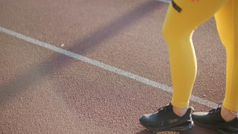 mujer corriendo en una pista al aire libre con ropa deportiva en un campo atlético