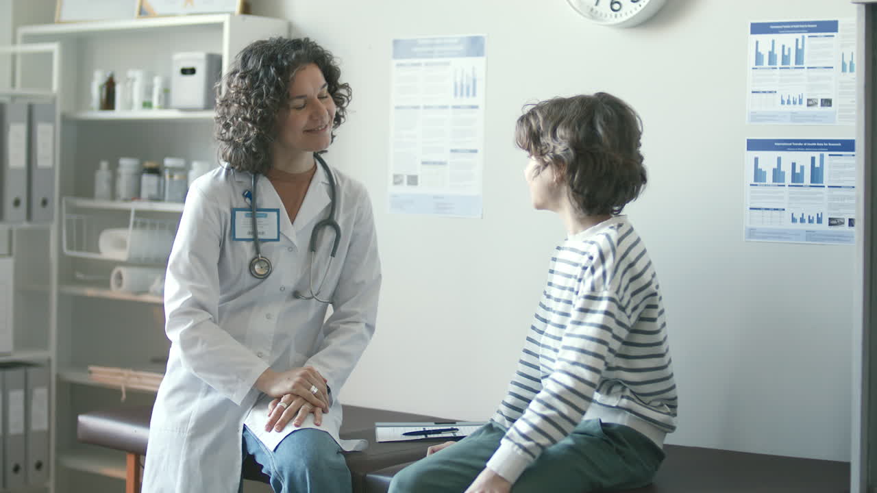 pediatra mujer estrechando la mano y hablando con un paciente joven en la clínica