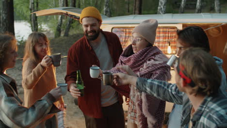 friends toasting and drinking from cups at campsite