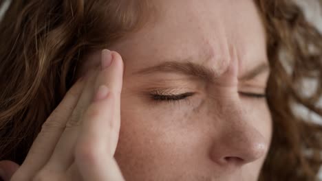 un primer plano extremo de estudio de una joven mujer caucásica con migraña.