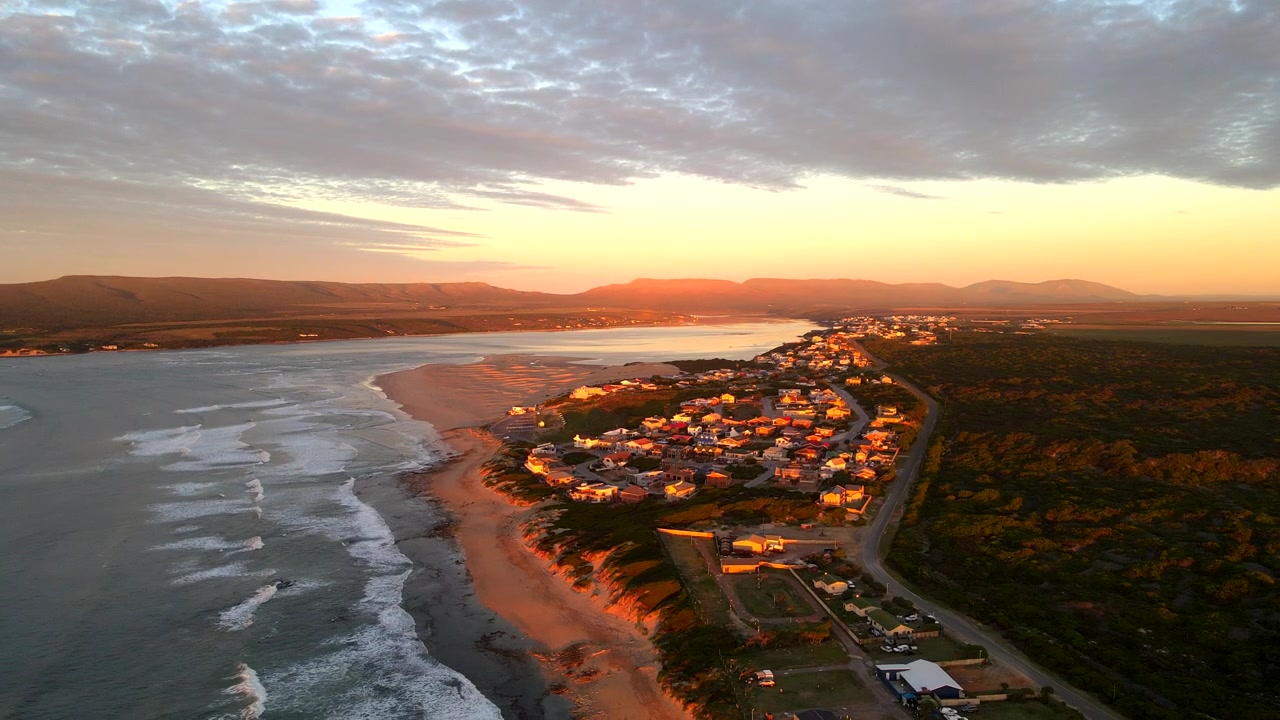 Vista aérea vibrante do nascer do sol sobre a praia, dunas e estuário da cidade costeira de Witsand.