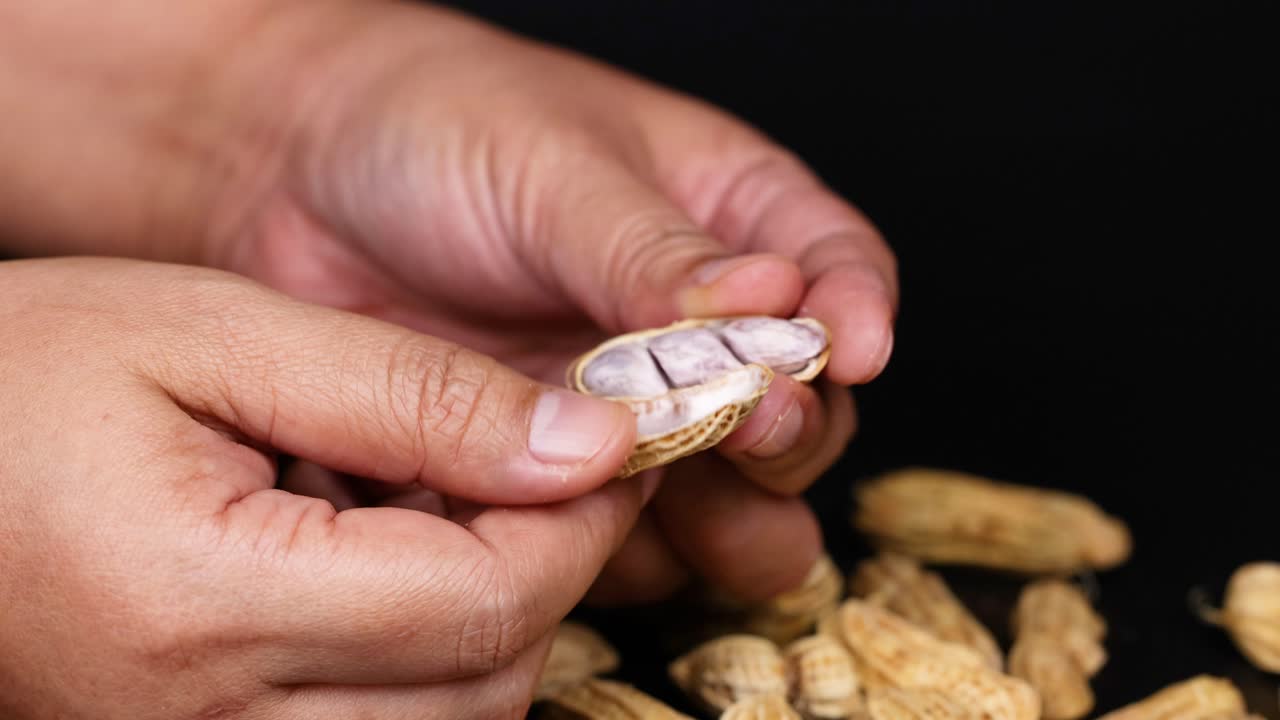 manos pelando cacahuetes, revelando las semillas dentro