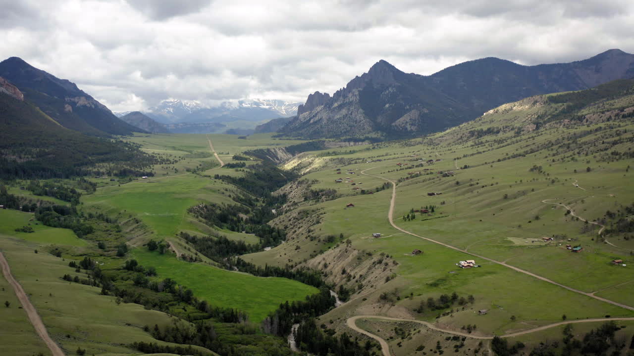 Panoramic view of a vast green valley with mountains and scattered rural homes under a cloudy sky