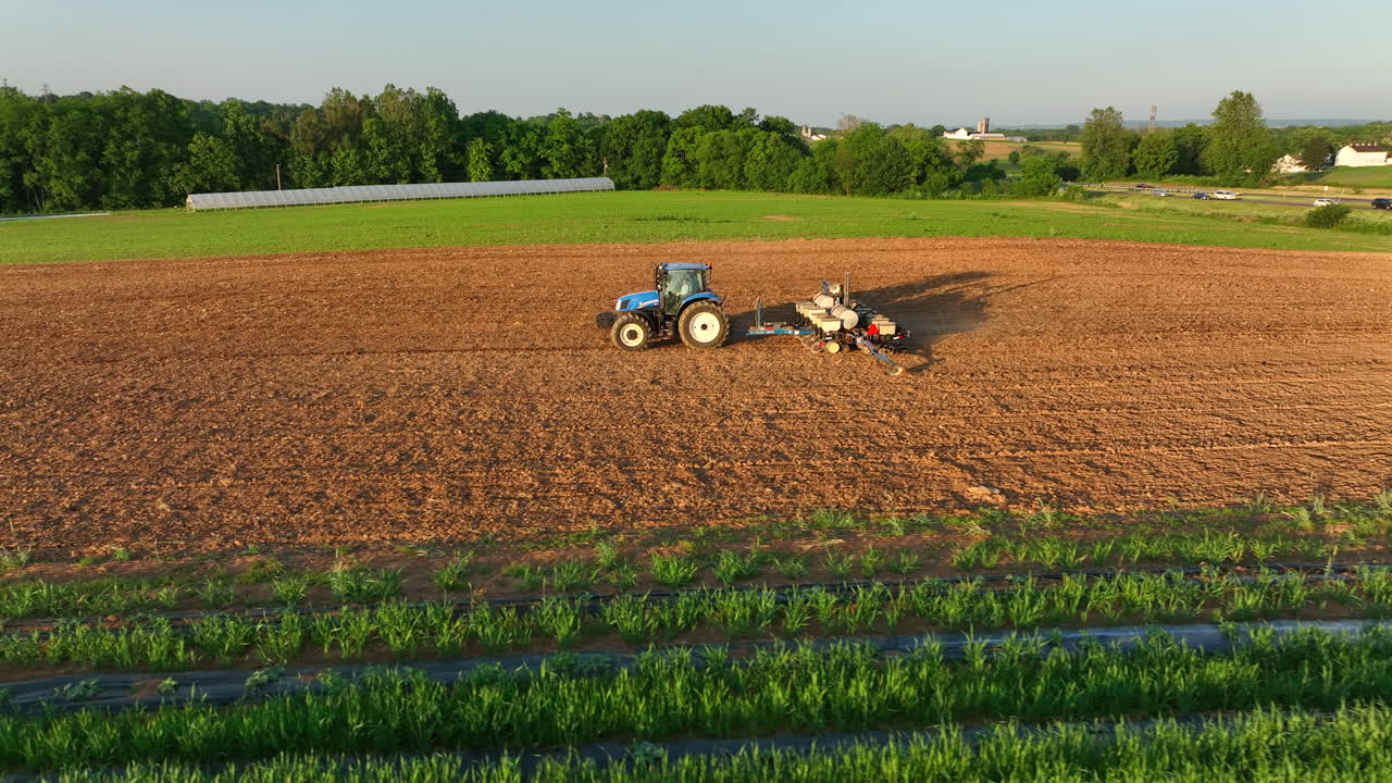 Aerial truck shot and orbit of New Holland tractor pulling seeder in rural Pennsylvania. American agriculture business theme. Beautiful lighting