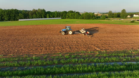 aerial truck shot and orbit of new holland tractor pulling seeder in rural pennsylvania. american agriculture business theme. beautiful lighting