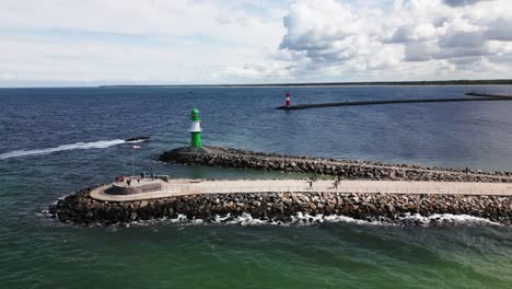 Lancha-Motora-Entra-Al-Puerto,-Dos-Luces-Del-Muelle-En-El-Puerto,-Faro,-Mar-Báltico,-Warnemünde,-Zumbido