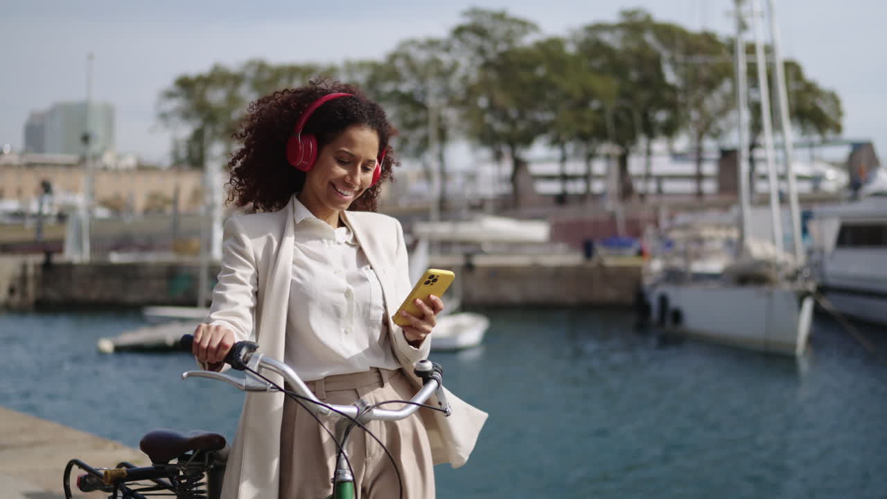 Woman with Bicycle, Headphones, and Mobile Phone by Waterfront