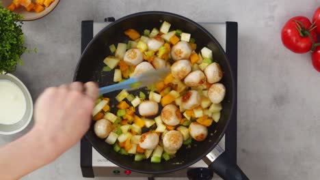 crop person adding meatballs to stew