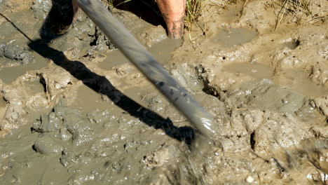 feet and pole stirring mud