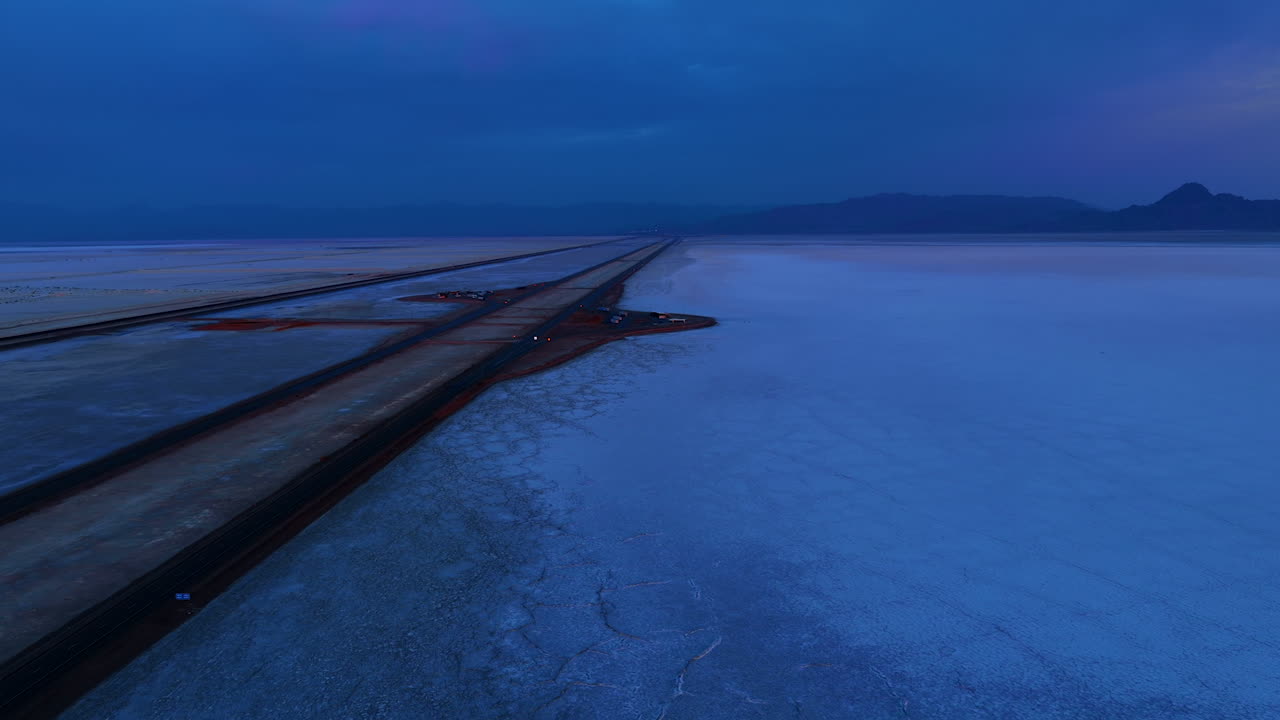 Trayectos solitarios en coche por la carretera en la inmensa llanura salada. Vídeo sobre las Salinas de Bonneville, Utah, Estados Unidos al atardecer