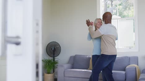 Una-Pareja-De-Ancianos-De-Raza-Mixta-Bailando-Juntos-En-El-Salón-De-Casa