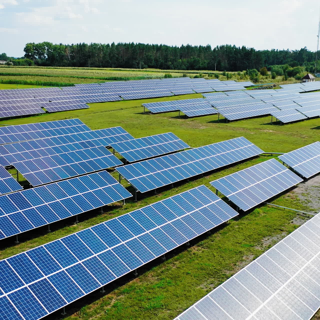 Drone view of solar energy panels in the field. Contemporary solar plant on the natural rural background. Camera moves rising up.