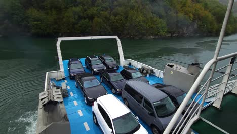 Ferry-Se-Prepara-Para-Zarpar-Desde-El-Muelle,-Embarcado-Con-Autos,-Motores-Rugiendo,-Emitiendo-Humo-Sobre-Las-Tranquilas-Aguas,-Salida-Del-Lago-Fierza