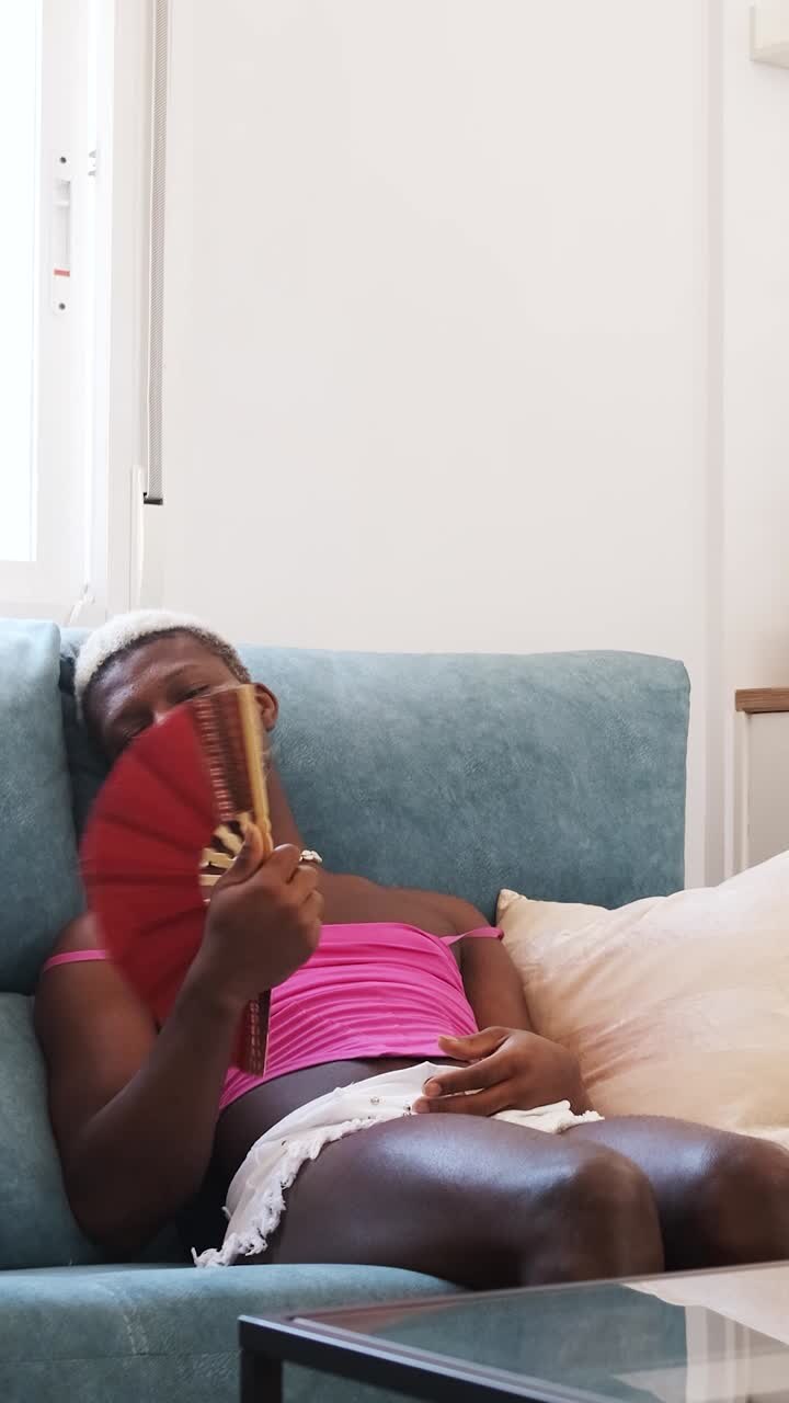Person fanning themselves on a sofa to cool down
