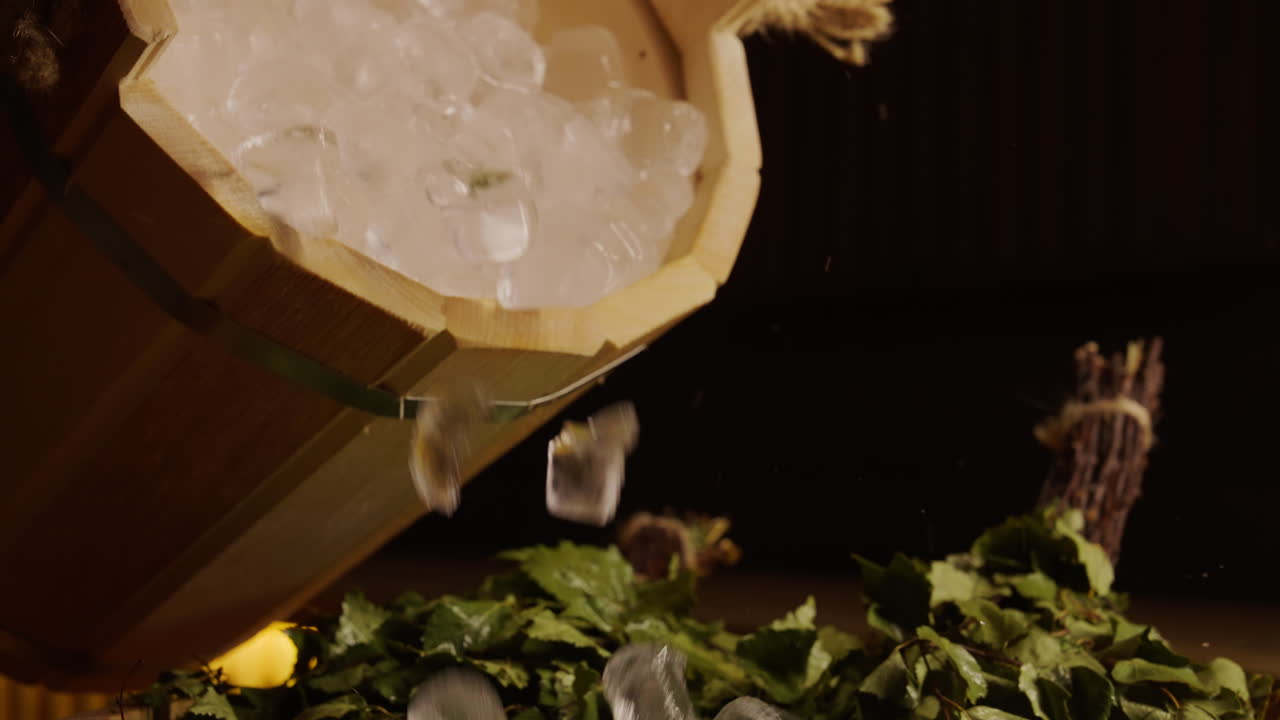 Ice Pouring into Wooden Sauna Bucket with Birch Branches