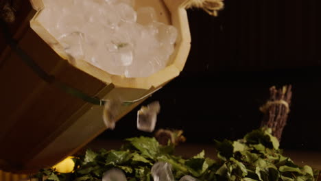ice pouring into wooden sauna bucket with birch branches