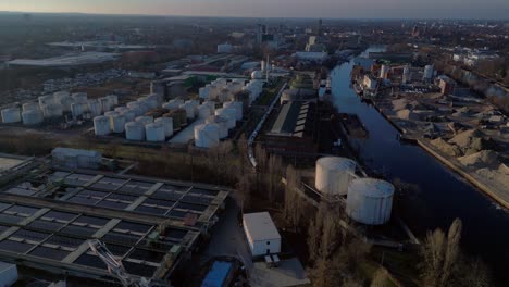 berlin biogas plant with its large white tanks reflecting on the river next to it during sunset. unbelievable aerial view flight panorama overview drone